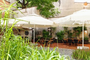 An outdoor patio with white umbrellas, wicker furniture, and potted plants.