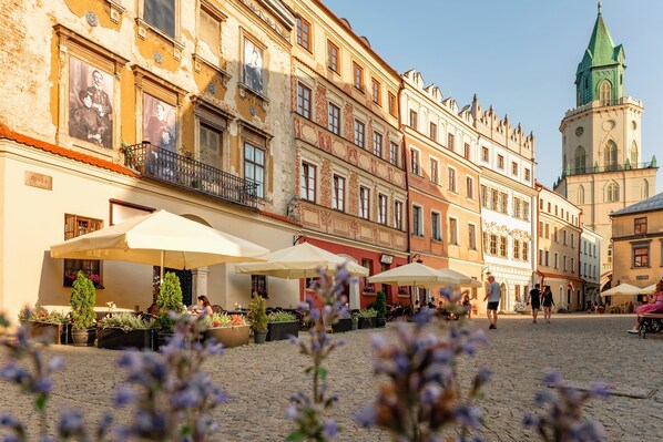 A cobblestone square with outdoor seating and a historic building with a green tower.