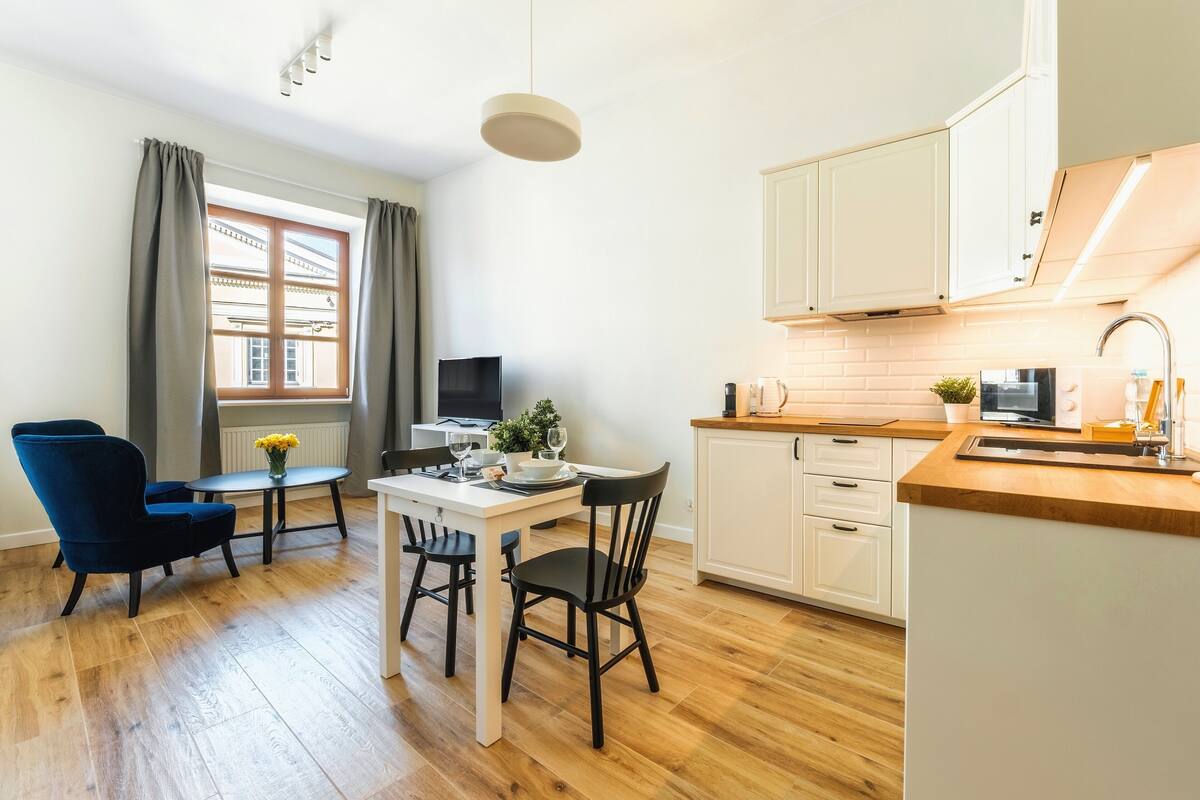 A modern kitchen with white cabinets, a wooden countertop, and a dining area with a table and chairs.