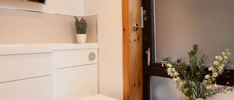 A modern bathroom with a toilet, a vanity, a mirror, and a window with a wooden frame.