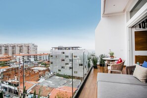 En moderne lejlighed med balkon, udsigt over byen og et spiseområde med bord og stole.