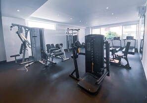 Et fitnesscenter med forskellig træningsudstyr, herunder styrkemaskiner og løbebånd.