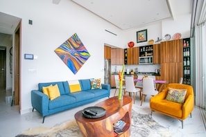 Una sala de estar moderna con un sofá azul, un sillón naranja y una mesa de centro de madera.