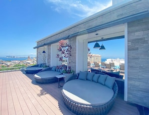 Terraza en la azotea con vistas a la ciudad, que incluye un rincón de estar con cojines y jardineras.