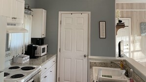 A kitchen with white cabinets, a white stove, a microwave, and a hanging light fixture.