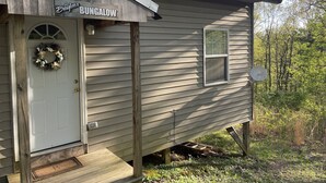 A small wooden bungalow with a porch, a door with a wreath, and a sign that reads "Braylee's Bungalow."