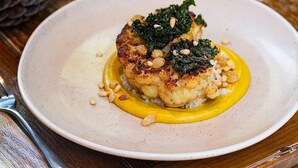 A plate of food on a table with a glass of water and a pine cone in the background. - The Bottle & Glass Inn – Garden View Room 1 (Henley-on-Thames)