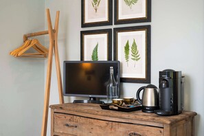 En trækommode med et fjernsyn, kaffemaskine og en bakke med kopper.