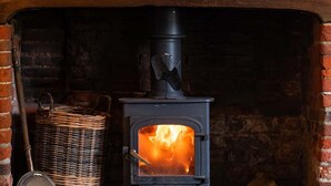 A traditional wood-burning stove with a sign above listing various beers and their prices. - The Bottle & Glass Inn – Barn View Room 2 (Henley-on-Thames)