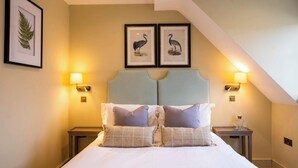 A neatly made bed with two pillows, a headboard, two wall-mounted lamps, and two framed pictures of birds on the wall. - The Bottle & Glass Inn – Barn View Room 2 (Henley-on-Thames)