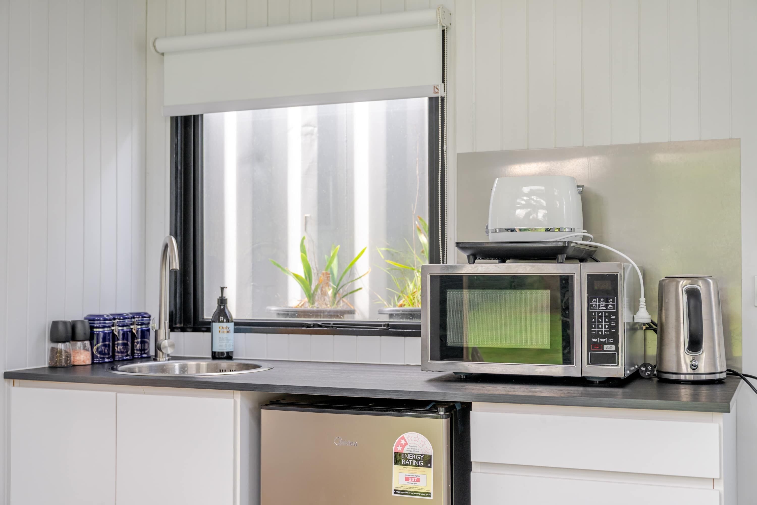 Une cuisine compacte équipée d’un four à micro-ondes, d’une bouilloire et d’un évier.