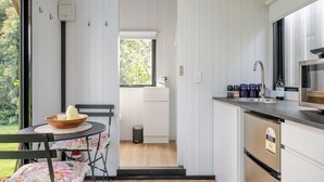Une cuisine de taille réduite comprenant un coin repas, une fenêtre et une porte donnant sur une salle de bain.