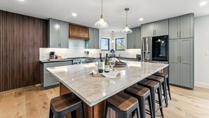 A modern kitchen with a large island, grey cabinetry, and stainless steel appliances. - Ski-In/Ski-Out Breckenridge Retreat with Hot Tub (Breckenridge)