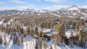 Una cabaña rodeada de árboles nevados y montañas.