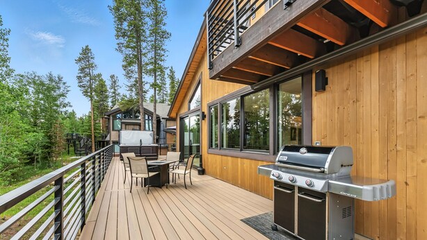 A wooden deck with a grill and outdoor seating area, overlooking a forested area. - Ski-In/Ski-Out Breckenridge Retreat with Hot Tub (Breckenridge)