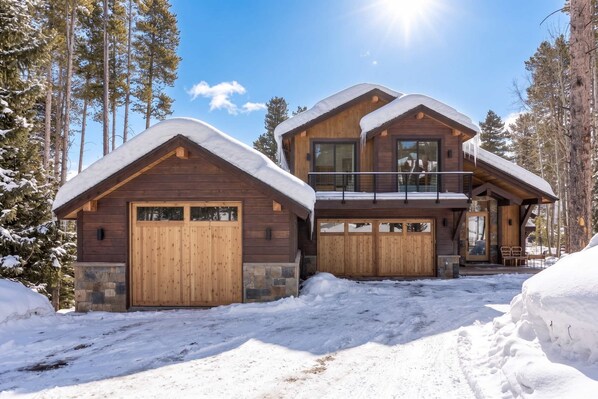 Een houten chalet met twee verdiepingen, een overdekte oprit en een balkon.
