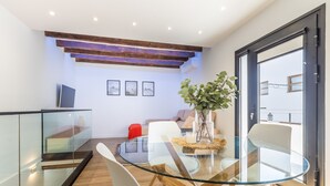 Et moderne spiseområde med et glasbord, hvide stole og en rød sofa.
