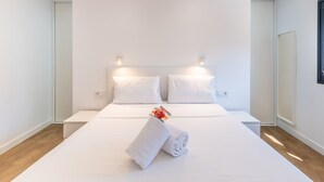 Et moderne hotelværelse med en stor seng, hvide sengetæpper og et pænt foldet håndklæde på sengen.