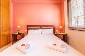 A hotel room with a large bed, two bedside tables with lamps, a wooden wardrobe, and a window with blinds. - 2BR Home with Parking - Mountain Views Terrace (Buenavista del Norte)
