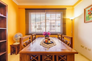 Enjoy meals in this cozy dining area with a table for four, a fan, and a vase with flowers.