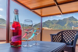 A table with a bottle of wine and two glasses on a balcony with a view of mountains. - 2BR Home with Parking - Mountain Views Terrace (Buenavista del Norte)