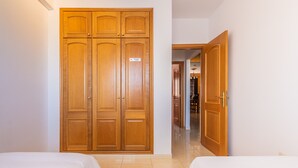 Habitación de hotel con dos camas, un armario de madera y un letrero que indica baño privado.