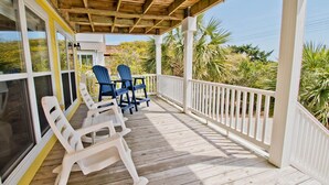 Eine Holzterrasse mit weißen Geländern und zwei blauen Stühlen.