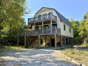 A two-story building with a balcony, a covered porch, and a gravel driveway.