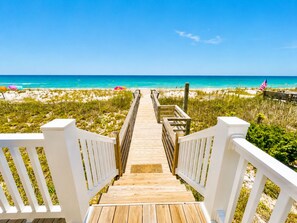A wooden boardwalk leading to a beach with an American flag. - Dolphin's Run, Oceanfront House in Emerald Isle, NC! (Emerald Isle)