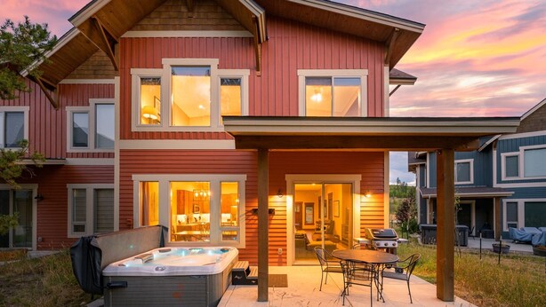 Une maison à deux étages dotée d’un patio couvert, d’un jacuzzi et d’un espace barbecue.