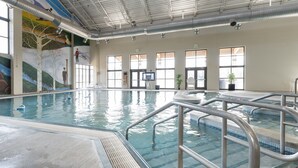 Une piscine intérieure avec des couloirs bien délimités, une fresque murale et de grandes fenêtres laissant entrer la lumière naturelle.