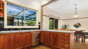 A spacious kitchen with wooden cabinets, a stainless steel dishwasher, and a large window overlooking a garden. - Relaxing farmhouse & panoramic views in Glenmore  (Glenmore)