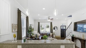 A spacious living area with a granite island, a ceiling fan, and a large window with curtains.