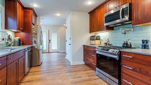 A kitchen with wooden cabinets, stainless steel appliances, and a tiled backsplash.