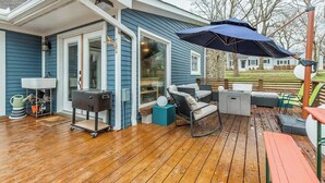 A deck with outdoor furniture, a grill, and a large umbrella.