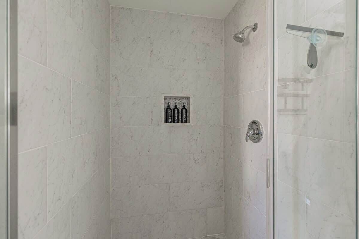 Eine gläserne Dusche mit Bedienfeld und Handtrockner.