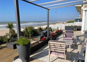 An outdoor patio with a view of the beach and ocean.