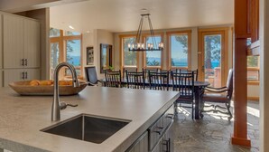 A modern kitchen with a large island, a dining area with a view, and a spacious layout. - Ramblin' Rose - Lakeview - TLUXP (Tahoe Vista)