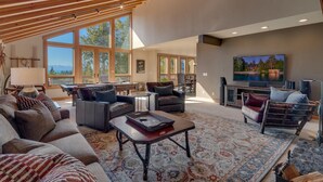 A spacious living room with large windows, a fireplace, and a television. - Ramblin' Rose - Lakeview - TLUXP (Tahoe Vista)