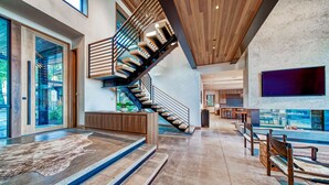 A spacious living area with a modern staircase, a large flat-screen TV, and a seating area with a rug. - Peace of Tahoe - Lakefront - TLUXP (Carnelian Bay)