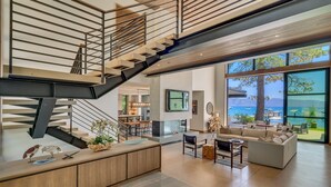 A modern interior with a staircase, a living area with a sofa and coffee table, and a view of the sea. - Peace of Tahoe - Lakefront - TLUXP (Carnelian Bay)