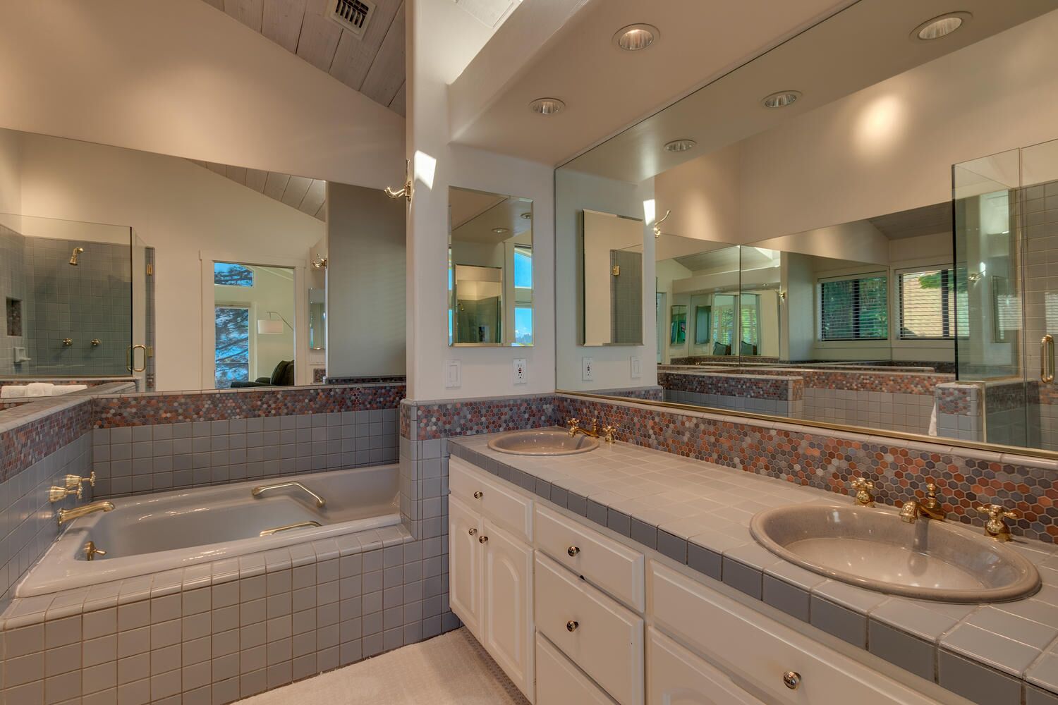 A modern bathroom with two sinks, a large mirror, and a bathtub.