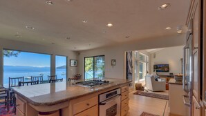 Una cocina moderna con una isla grande, un comedor con vistas al mar y un espacio de sala de estar acogedor con chimenea.