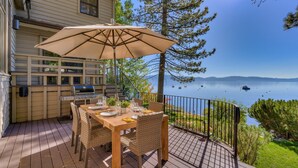 Terraza con mesa y sillas, una parrilla y vistas al lago.