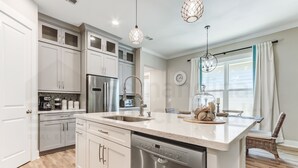 A modern kitchen with white cabinets, stainless steel appliances, and a large island with a dishwasher.