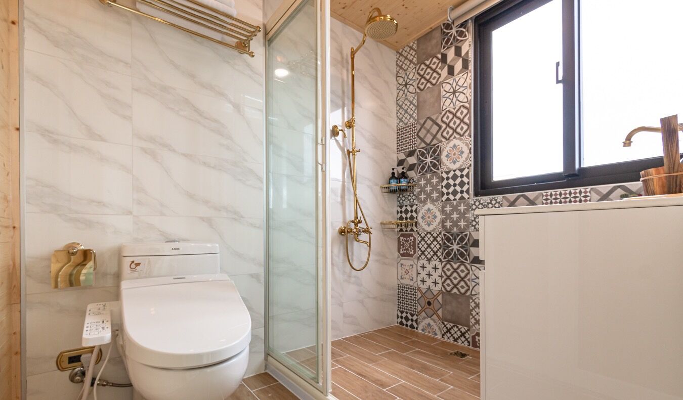 A bathroom with a glass-enclosed shower, a toilet, and a sink with a faucet.