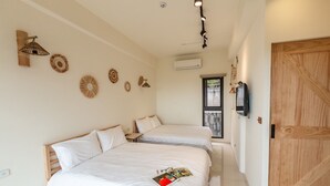 Una habitación de hotel con dos camas, una puerta de madera, un televisor y decoración en las paredes.