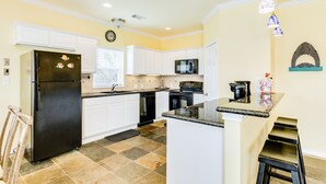 A kitchen with white cabinets, a black refrigerator, a microwave, and a sink. - Dog Friendly, Private Beachside Home in Pirates Beach w/ Covered Deck (Galveston)