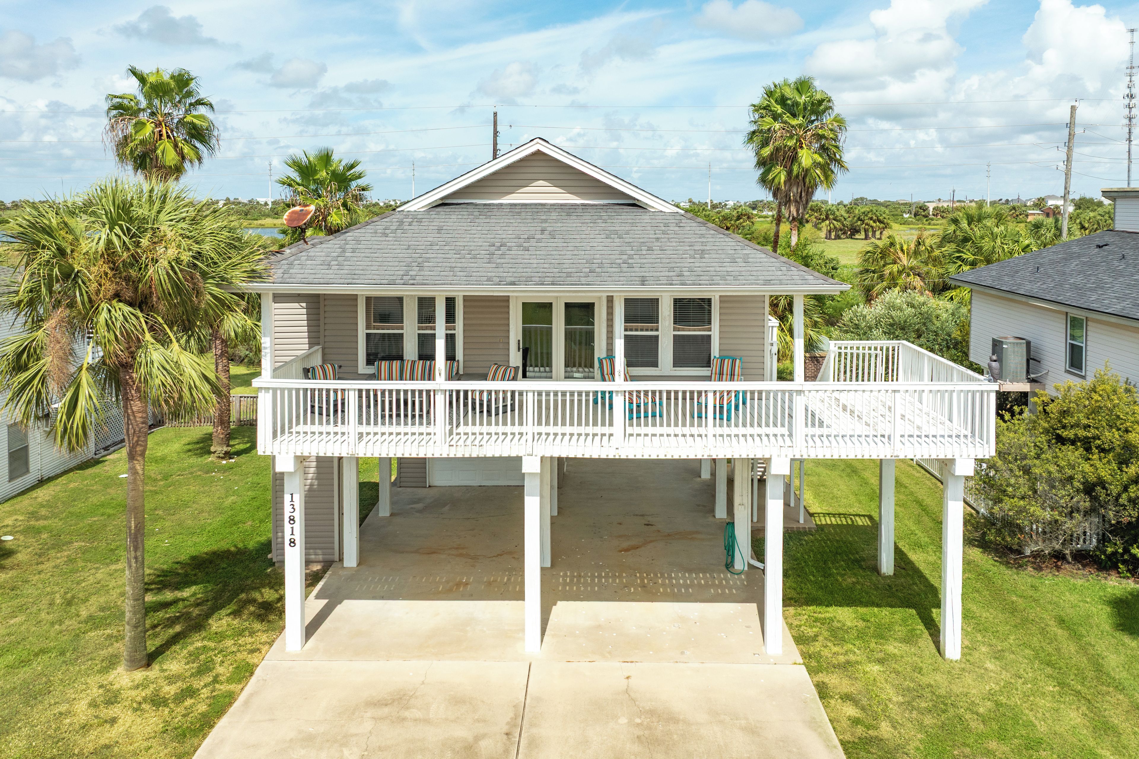 A two-story house with a covered porch, a garage, and a number '13818' on the post.