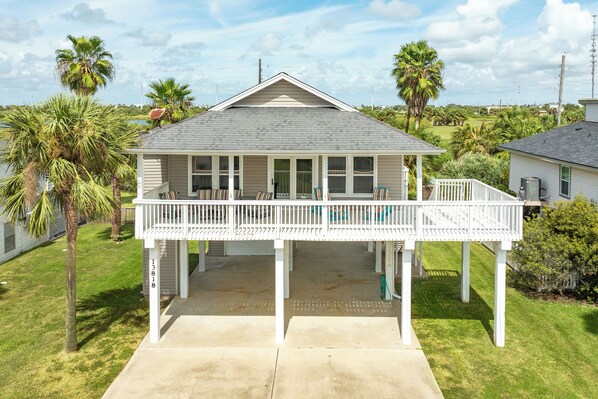 A two-story house with a covered porch, a garage, and a number '13818' on the post.